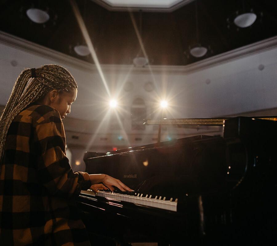 亩ic student plays the piano in an auditorium.